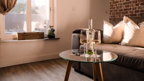 Una sala de estar con una mesa de vidrio, un sofá y una botella de vino.