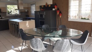 A modern kitchen with a central island, bar stools, and a dining table with chairs. - single-storey house 600 m beach (Étables-sur-Mer)
