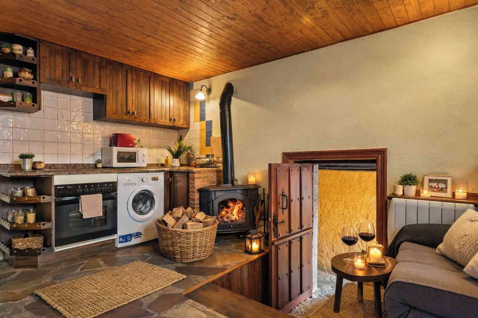 Una cocina acogedora con estufa de leña, lavadora y comedor con mesa y sillas.