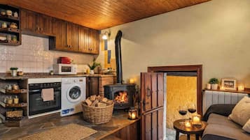 Una cocina acogedora con estufa de leña, lavadora y comedor con mesa y sillas.