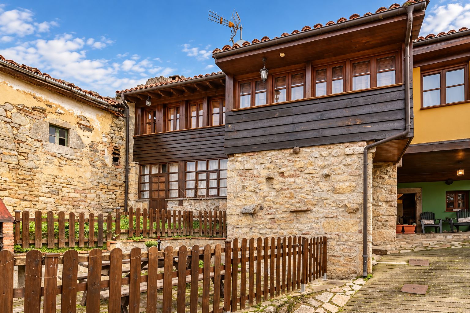 A traditional stone building with a wooden balcony and a wooden fence.