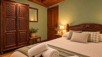 Un dormitorio con un armario de madera grande, una cama con varias almohadas, una mesita de noche con una lámpara y una pared verde.