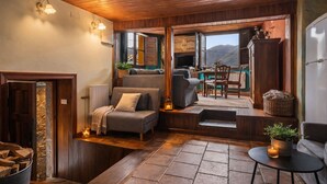 Un salon chaleureux avec un canapé, une table à manger et une vue sur les montagnes par une grande fenêtre.