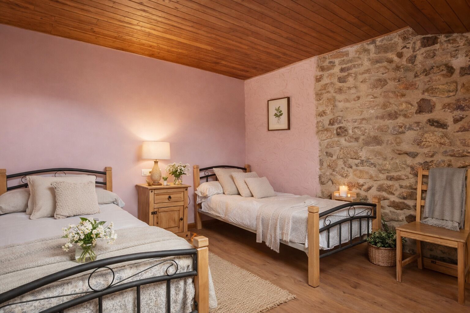 Ein Schlafzimmer mit zwei Betten, einer Steinwand, einer Holzbalkendecke und einem kleinen Tisch mit Lampe.