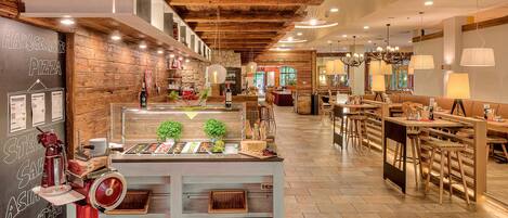 Interior de un restaurante con techo de madera, un mostrador de buffet y zonas de estar.