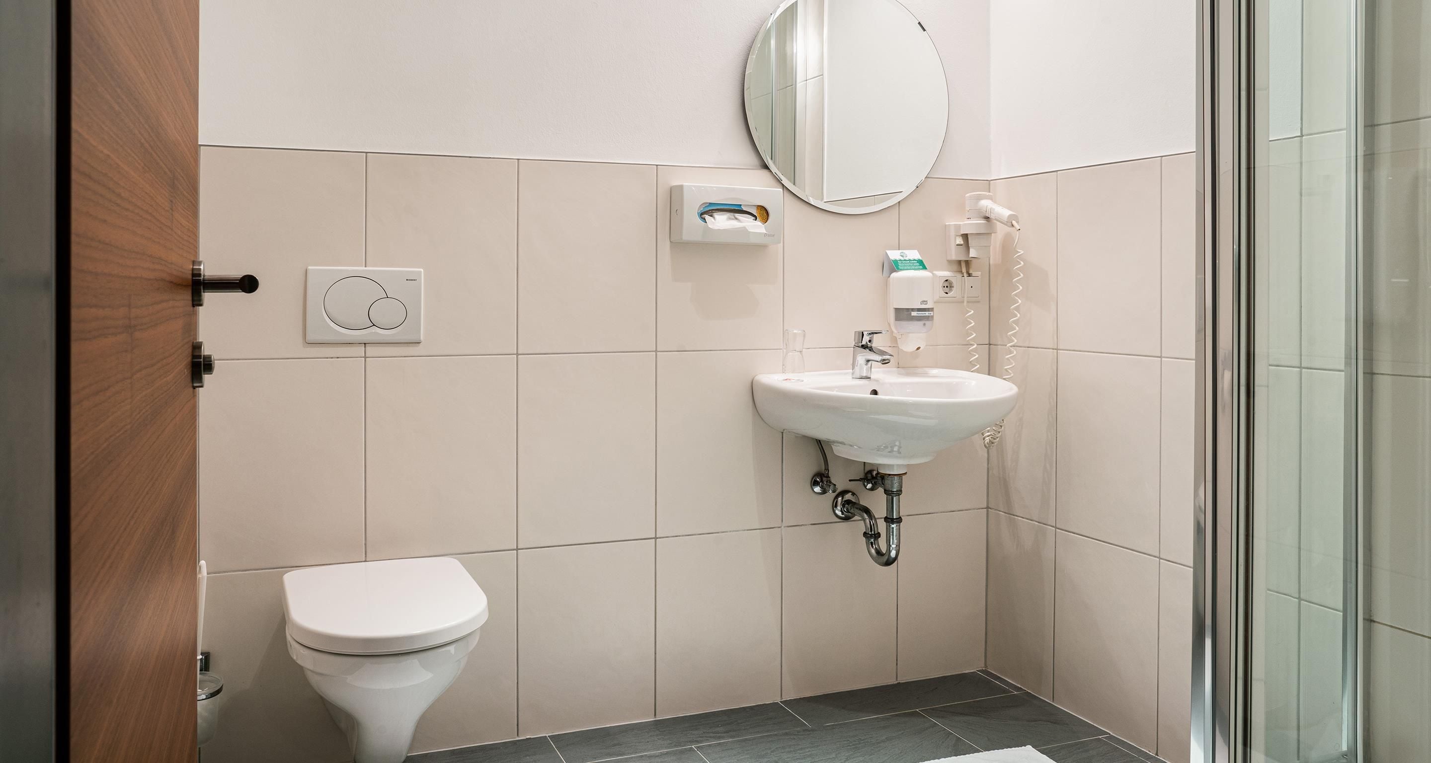 Ein Badezimmer mit Toilette, Waschbecken, Spiegel und Handtrockner.