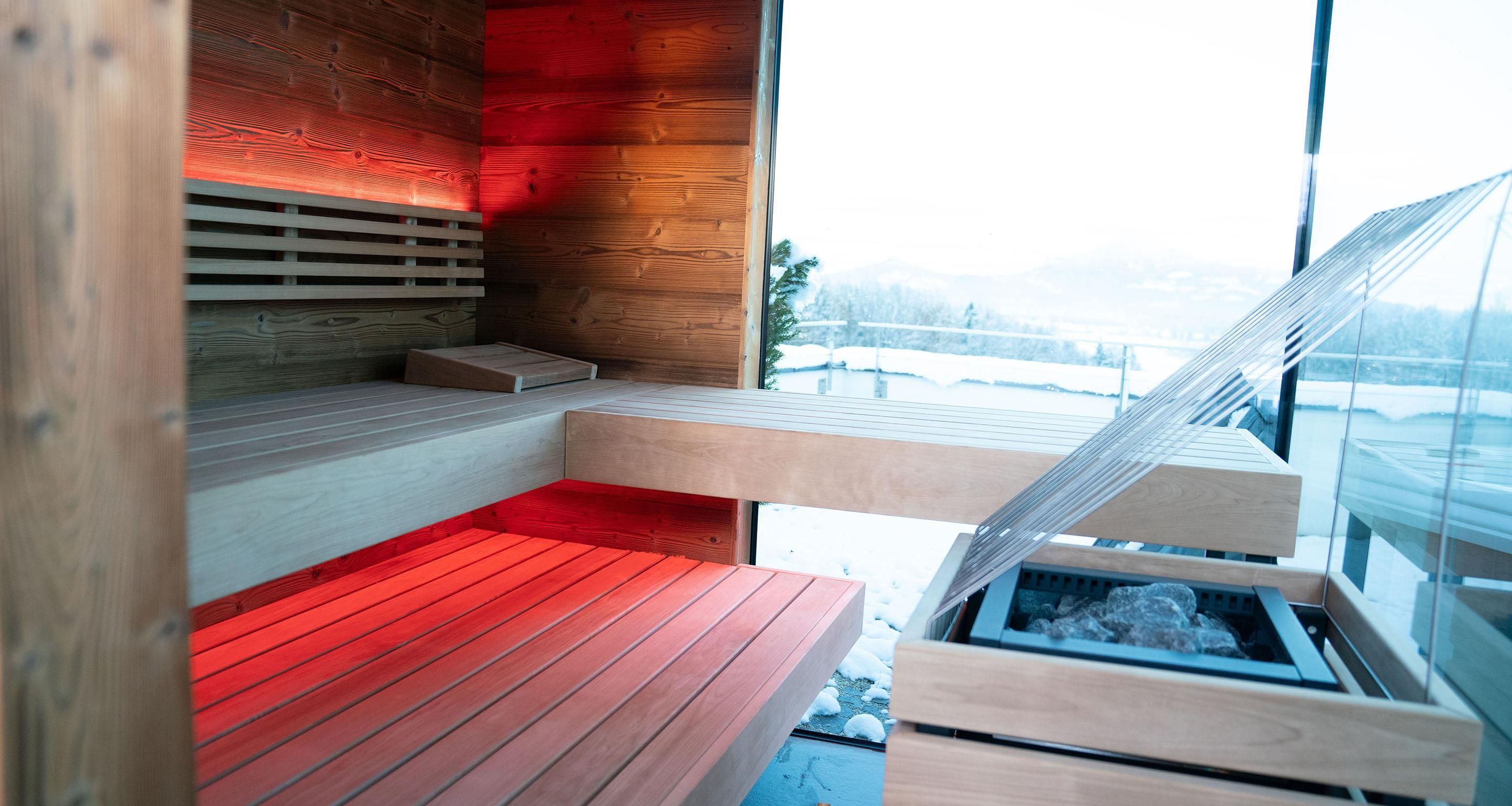 A modern interior with wooden slatted walls, a bench, and a window overlooking a snowy landscape.
