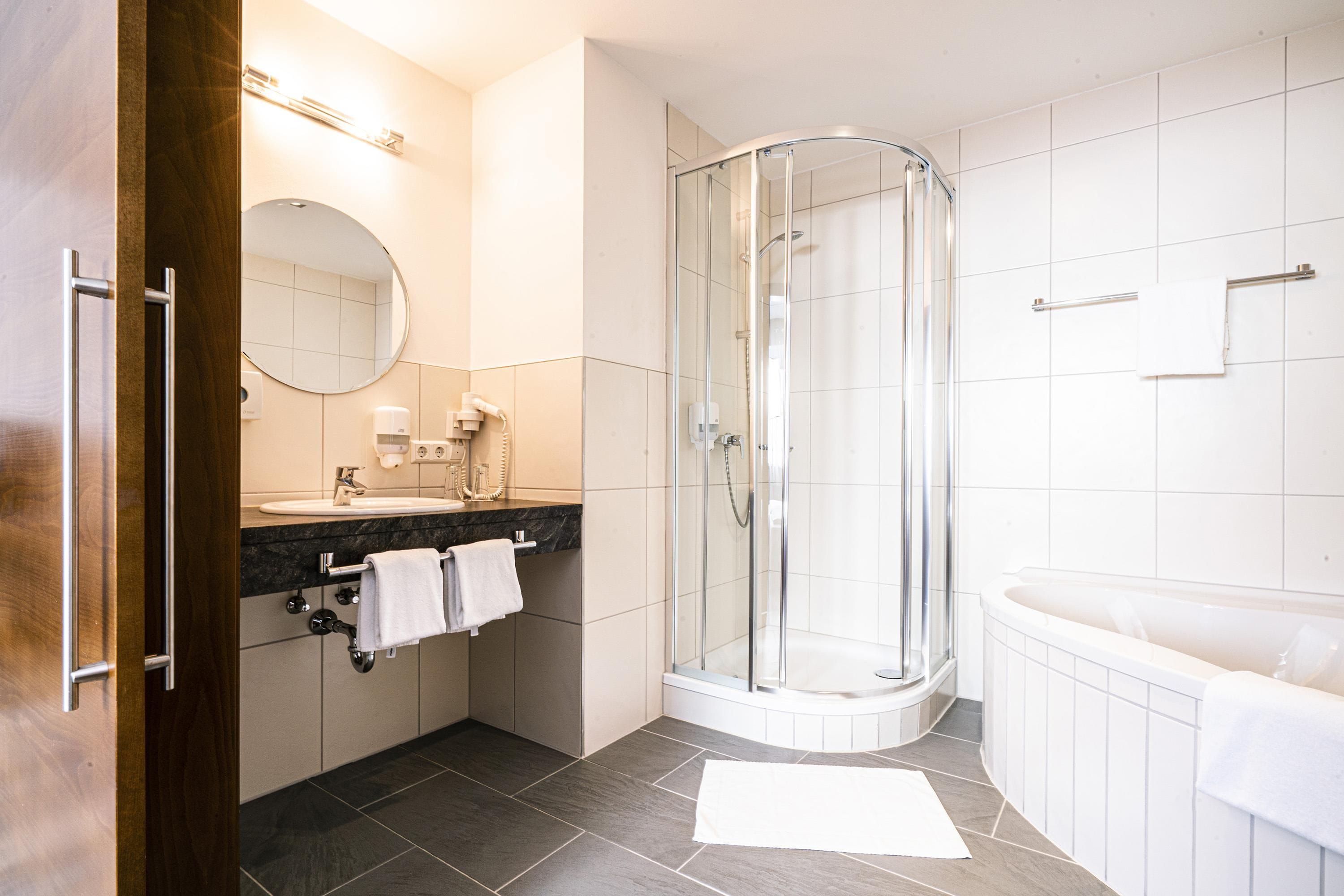 Un baño moderno con cabina de ducha de vidrio, bañera y tocador con espejo.