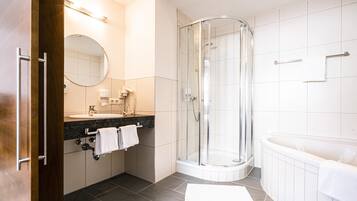 Un baño moderno con cabina de ducha de vidrio, bañera y tocador con espejo.