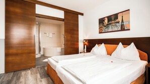 Habitación de hotel con una cama grande, cabecero de madera y un cuadro de un paisaje urbano.