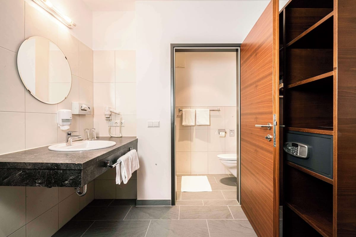 Un baño moderno con encimera de mármol, un espejo redondo y un armario de madera.