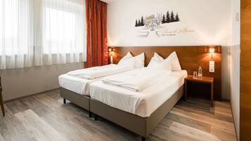Ein Hotelzimmer mit Doppelbett, einem Holznachttisch, einem Sessel und einer Wanddekoration.