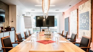 Un salón de conferencias con una larga mesa, sillas, un televisor y una pizarra.