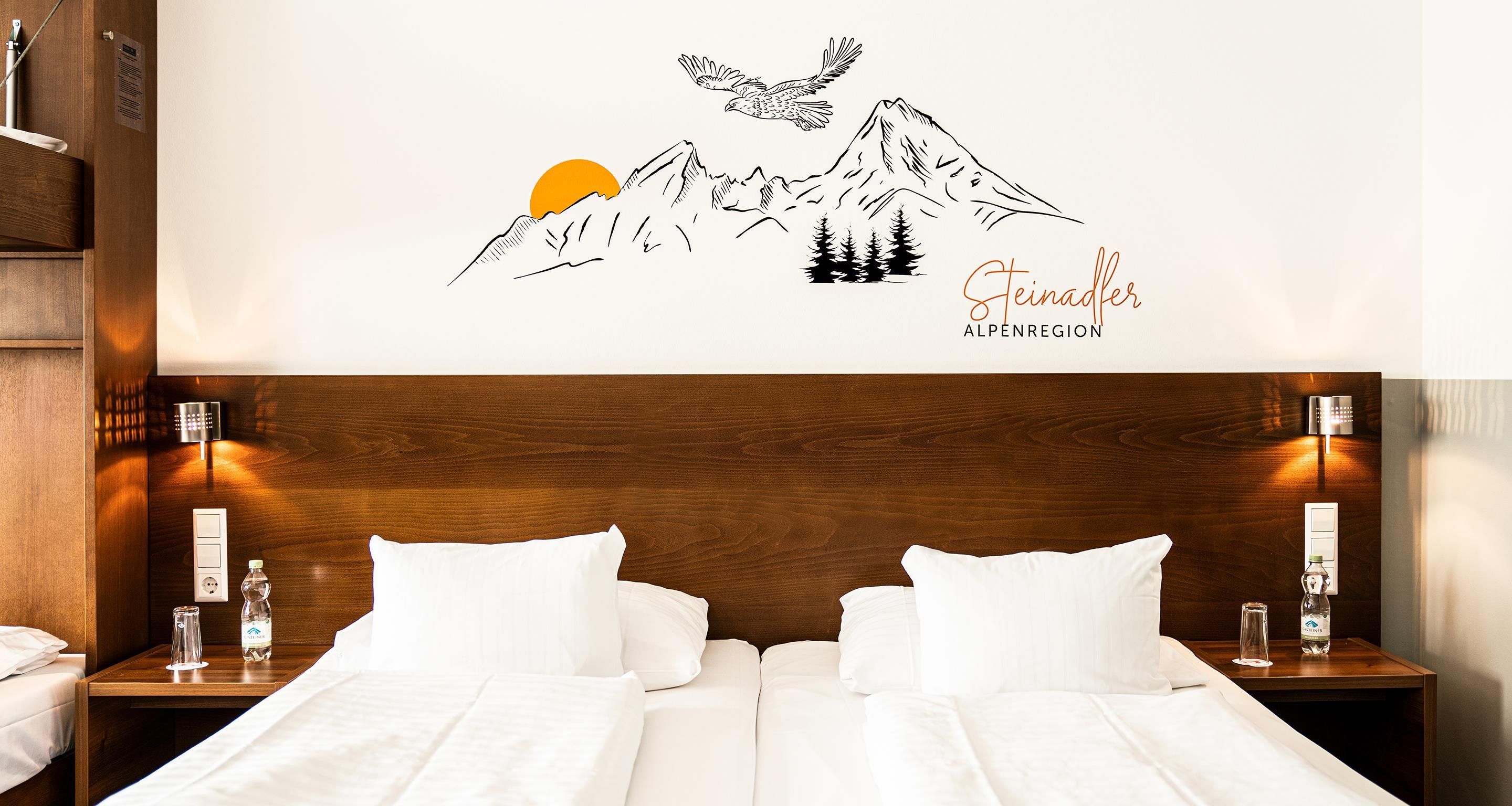A hotel room with a wooden headboard, two white beds, a wall-mounted artwork of a mountain scene, and two bedside lamps.