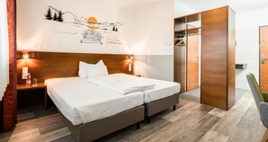 Une chambre d’hôtel comprenant un lit, des tables de chevet, une armoire et une fresque murale.