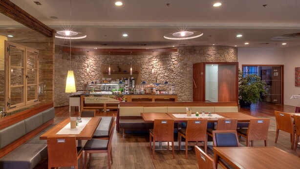 Ein Restaurant mit Holztischen und -bänken, einer Steinwand und einer Theke mit Speisekarte.