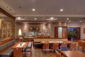 Ein Restaurant mit Holztischen und -bänken, einer Steinwand und einer Theke mit Speisekarte.