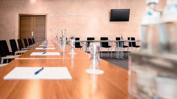 A conference room with a long table, chairs, and a television on the wall.