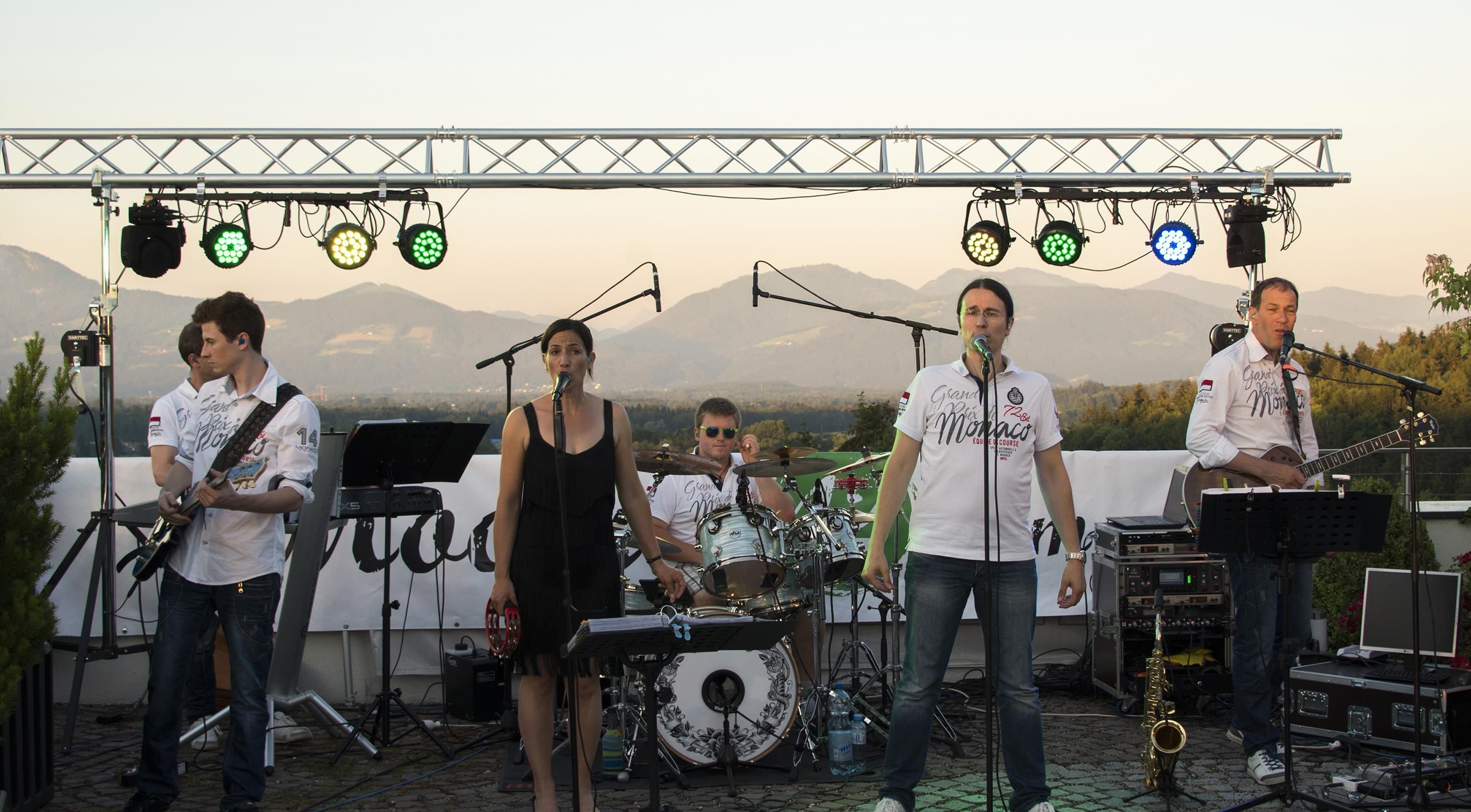 A band performing on an outdoor stage with mountains in the background.