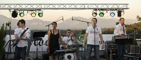 A band performing on an outdoor stage with mountains in the background.