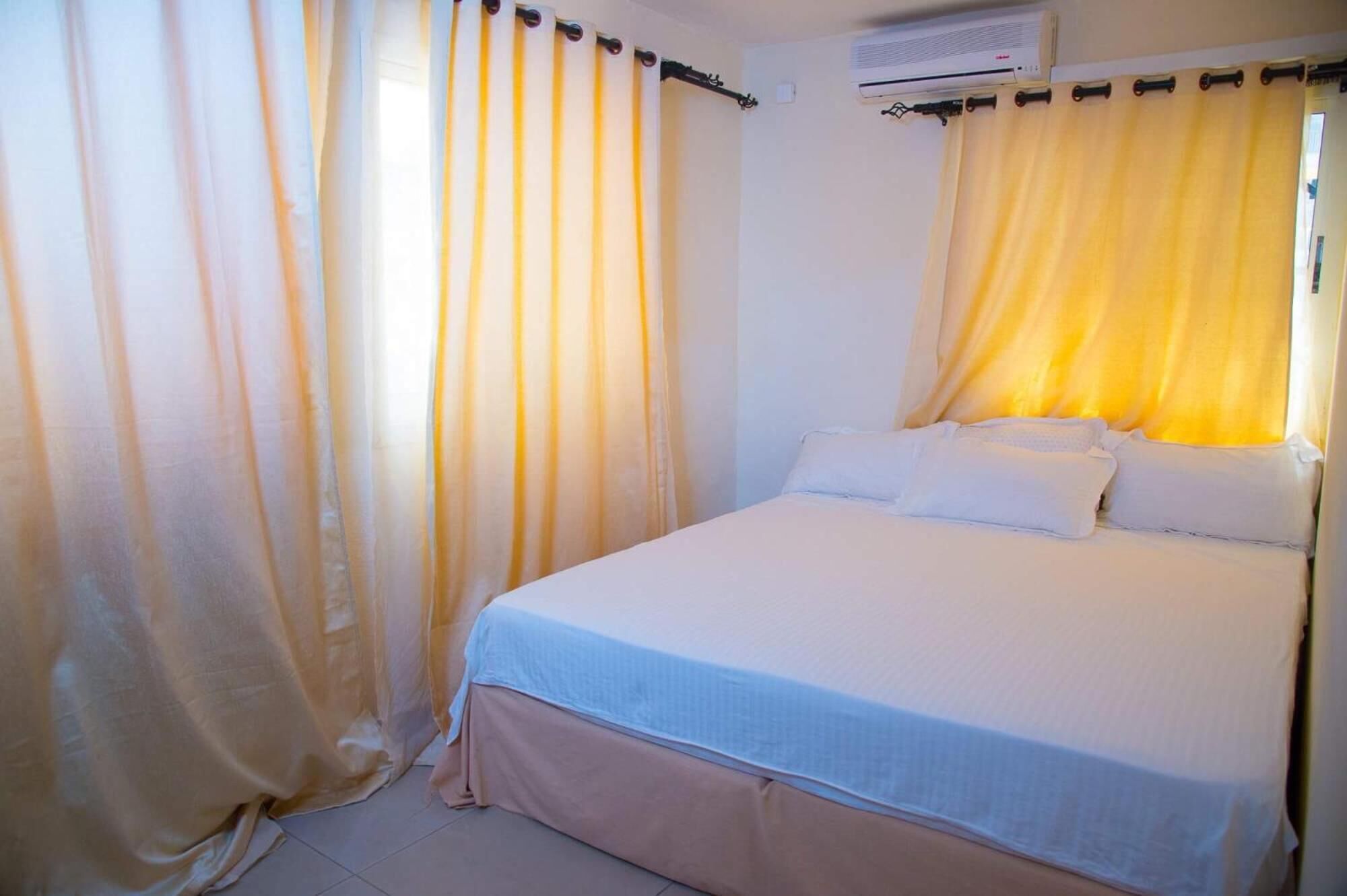 A bedroom with a bed, curtains, and an air conditioning unit.