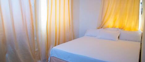 Un dormitorio con cama, cortinas y aire acondicionado.