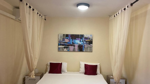 A hotel room with a bed, two nightstands, a painting on the wall, and curtains. - Residence Maeva (Mamoudzou)