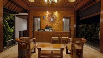 A reception area with a wooden reception desk, two cushioned chairs, a wooden coffee table, and a chandelier.