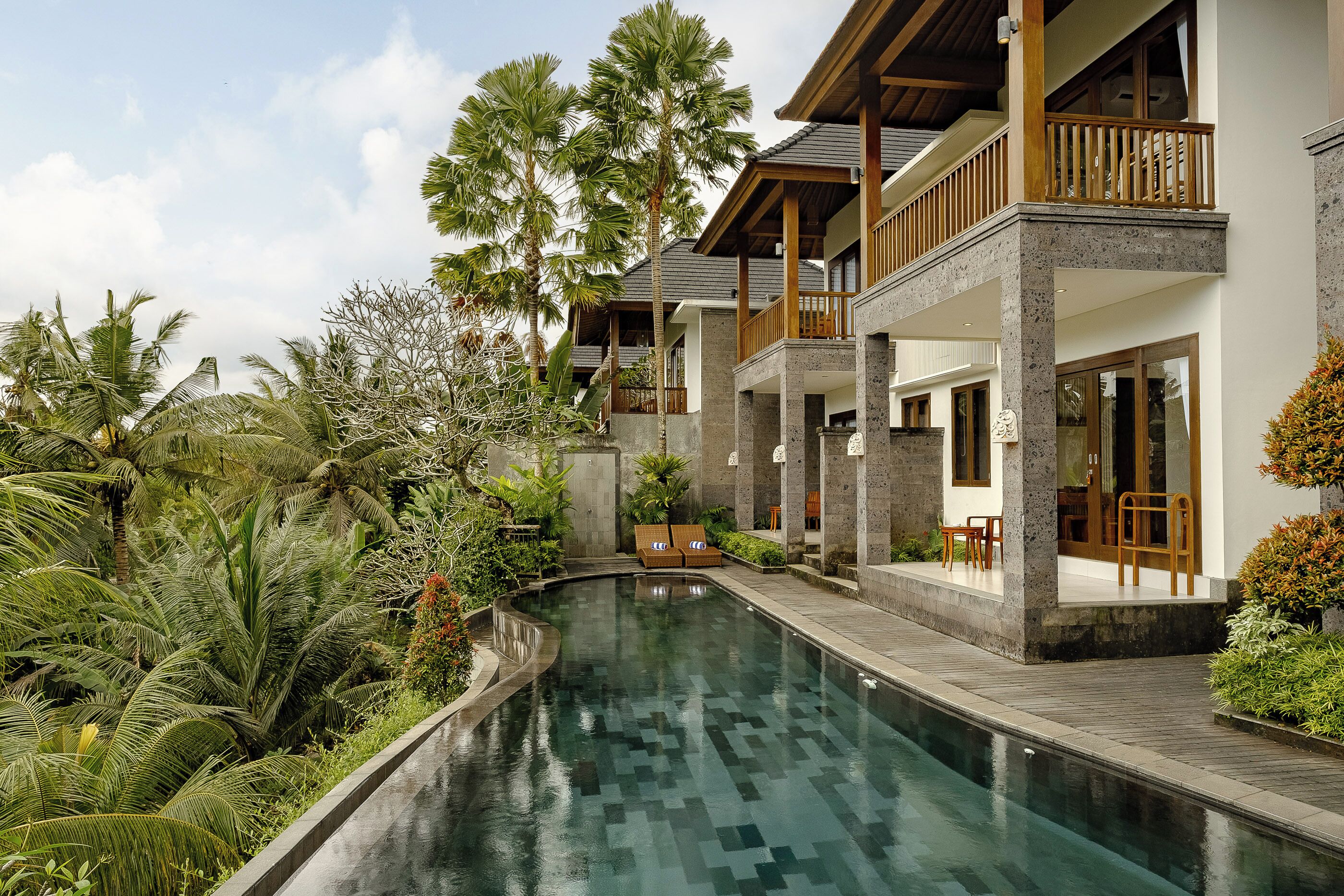 Ein modernes Resort mit Pool, Holzterrasse und üppiger Bepflanzung.