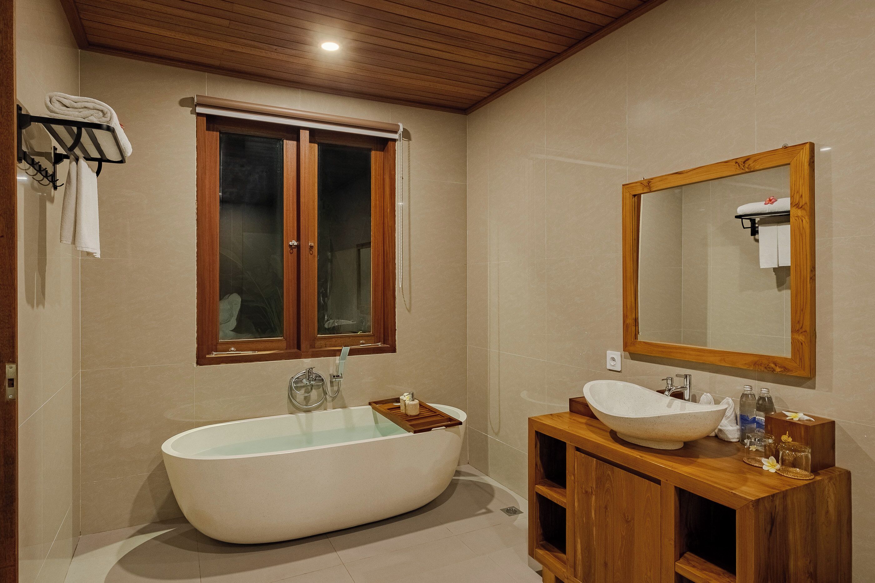 Un baño moderno con una bañera independiente, tocador de madera y un espejo grande.