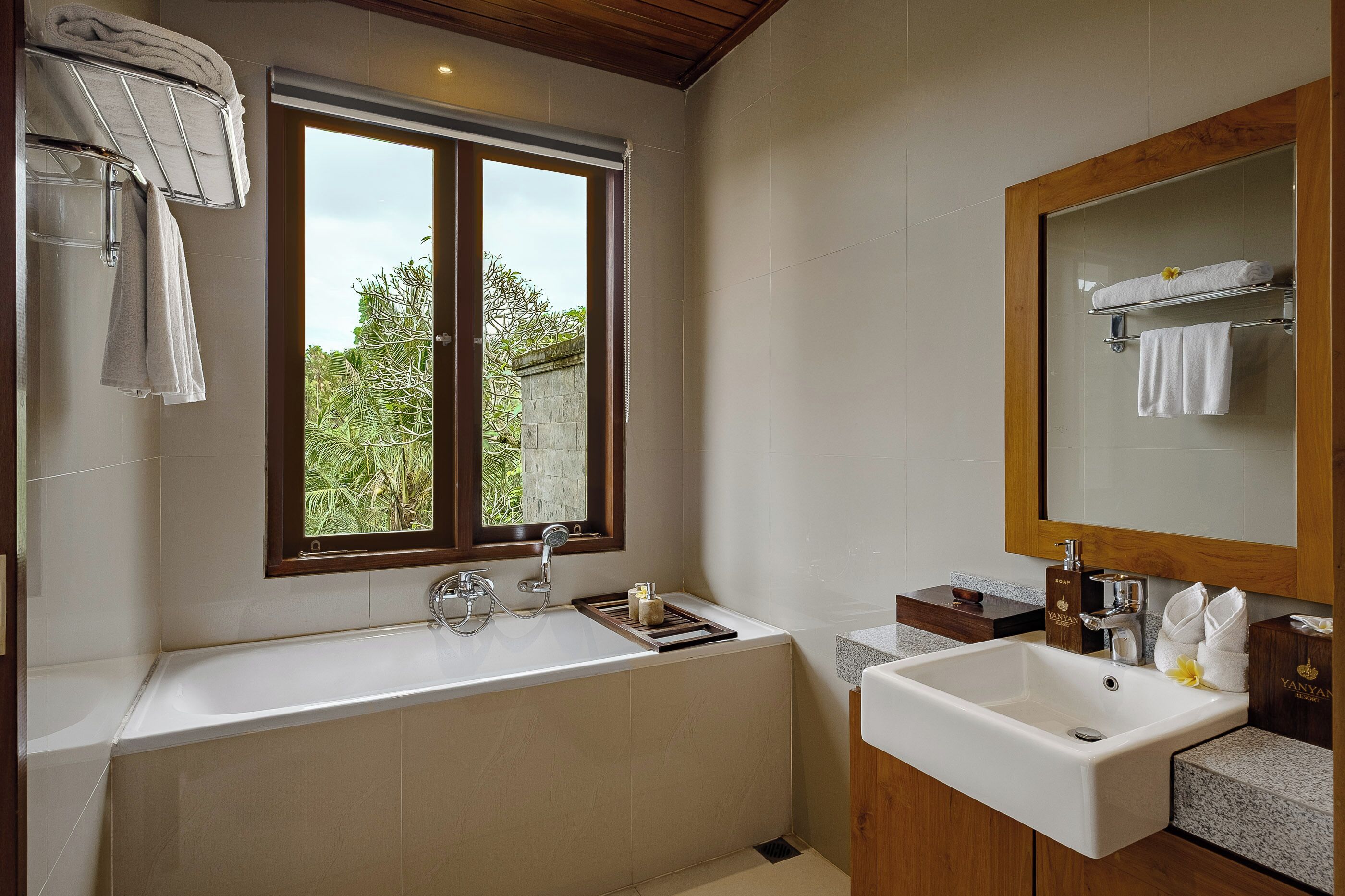 Un baño moderno con bañera, lavamanos y un espejo grande.