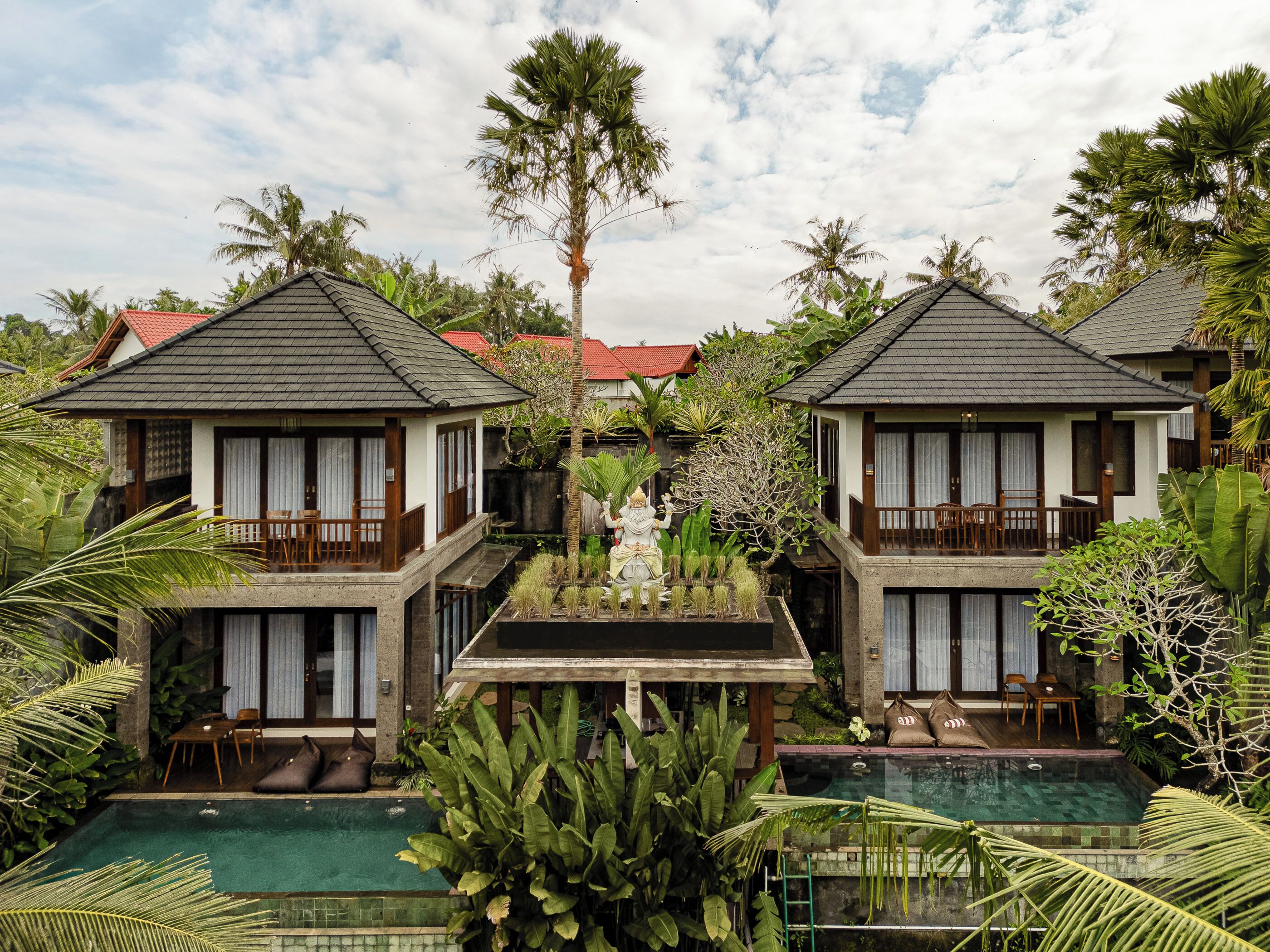 A resort with two-story buildings, a central pool, and lush tropical vegetation.