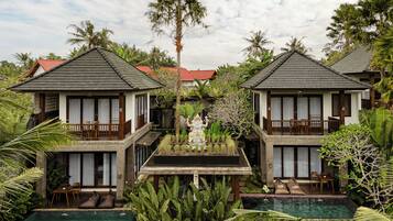 A resort with two-story buildings, a central pool, and lush tropical vegetation.