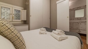 Ein Schlafzimmer mit Bett, Kommode und Spiegel.
