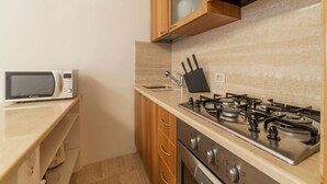 Eine kleine Küche mit Mikrowelle, Herd und Holzschränken.