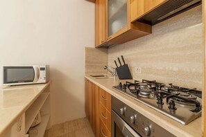 Una cucina compatta con forno a microonde, fornelli e mobili in legno.