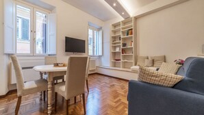 Ein Wohnzimmer mit Essbereich, einem Fernseher und einem Bücherregal.
