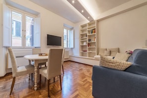Un soggiorno con zona pranzo, televisione e libreria.