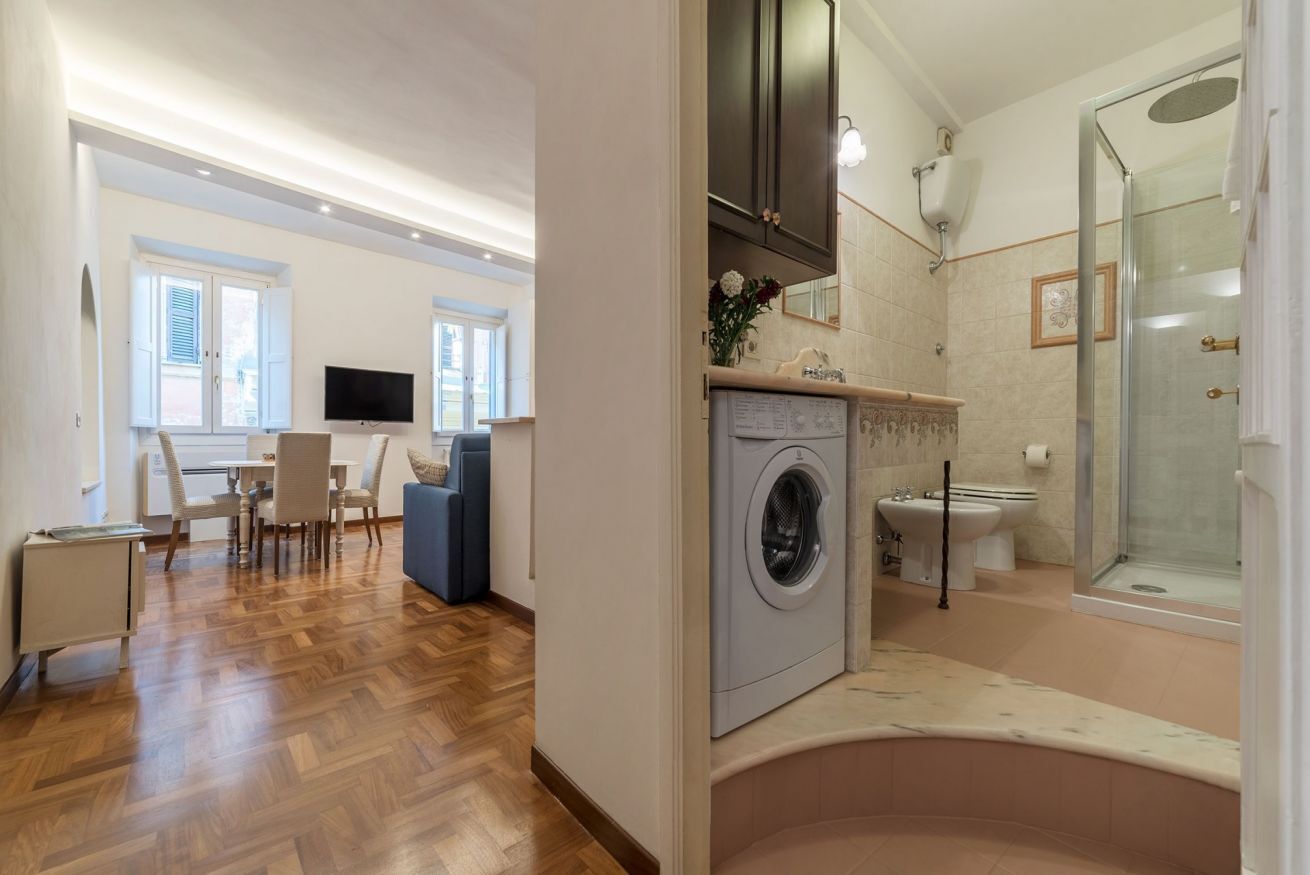 A modern apartment with a kitchen, dining area, and a bathroom with a shower and toilet.
