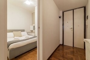A bedroom with a bed, a bedside table, a mirror, and a wardrobe.
