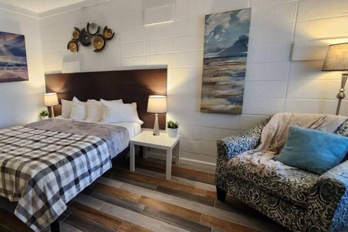 Une chambre à coucher avec un lit, des tables de chevet, une chaise et des œuvres d’art accrochées aux murs.