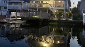 Et hus ved vandet med balkon, en anløbsbro og et spejlbillede i vandet.