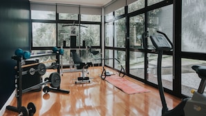 A gym with exercise equipment, large windows, and a wooden floor. - Vila Crerital - By Wehost (Funchal)