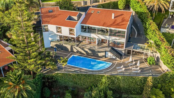A modern building with a swimming pool, surrounded by lush greenery.