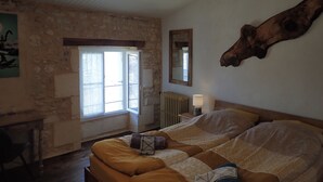 Un dormitorio con cama, cabecero de madera, espejo grande y pared de piedra.