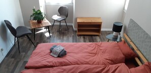 A bedroom with a bed, two chairs, a small table with a plant, a wooden bench, and a lamp. - La Miramboise (Mirambeau)