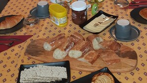 Una mesa de desayuno con diversos alimentos y bebidas, como pan, pasteles y café.