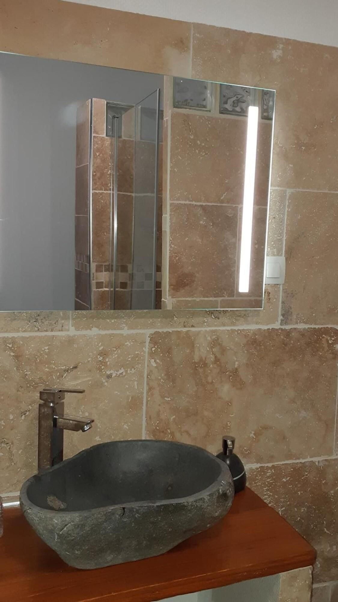 Un baño con un lavabo de piedra, un espejo y una pared con azulejos.