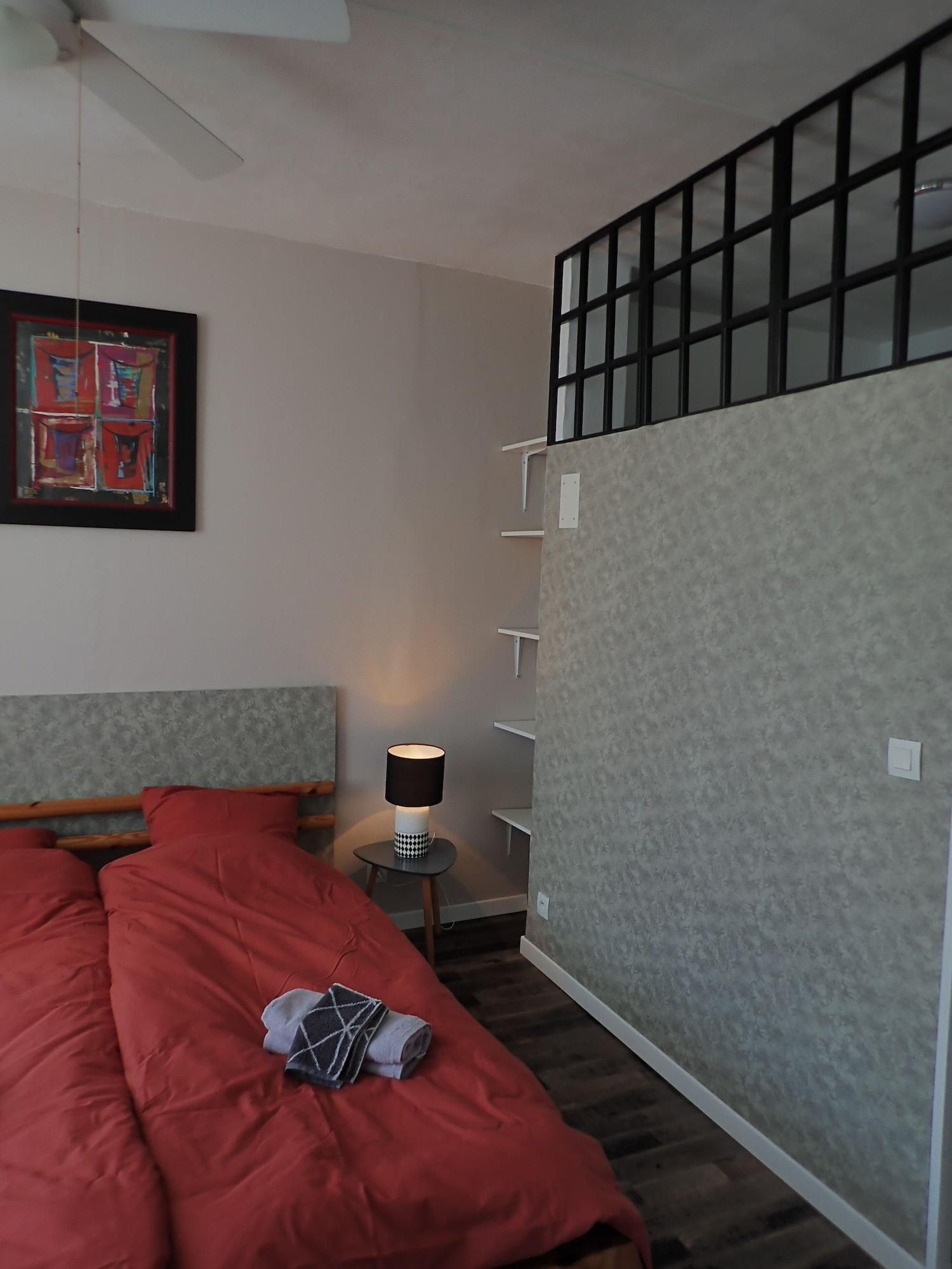 Une chambre à coucher avec un lit, une lampe, un tableau et une fenêtre avec des stores.