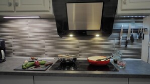 Una cocina moderna con extractor de acero inoxidable, salpicadero de azulejos y un soporte para cuchillos.